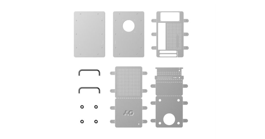 Flat-pack kit of the Computer-1 aluminum PC case featuring unassembled sheet metal panels, chrome handles, and hardware components laid out in a grid.