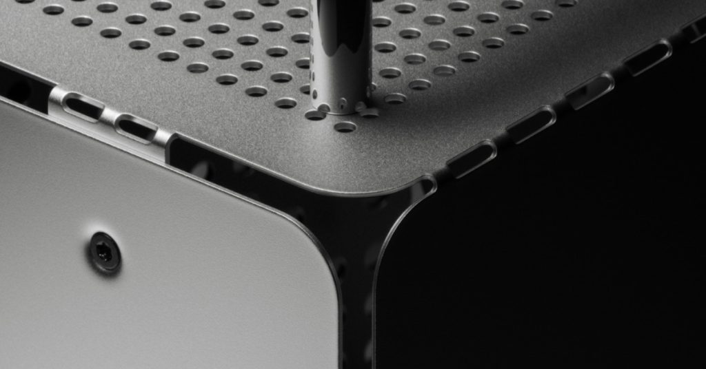 Close-up macro shot of the Computer-1 aluminum PC case showing the perforated metal top panel, a chrome handle, and a curved corner with precision industrial folds.
