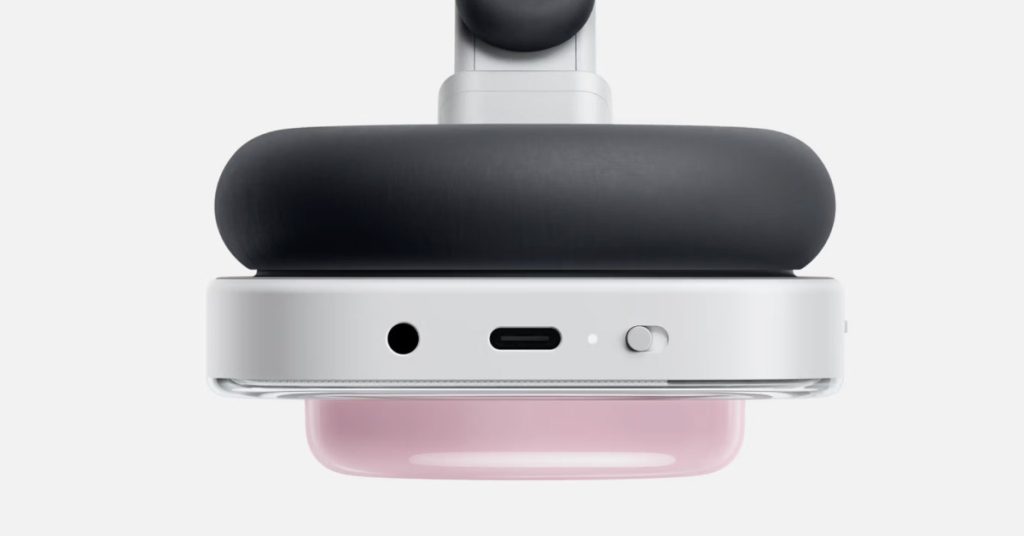 Bottom view of the pink Nothing Headphone (a), showing the USB-C charging port, 3.5mm audio jack, LED indicator, and mechanical power toggle switch. This highlights the practical connectivity and physical controls mentioned in the review.